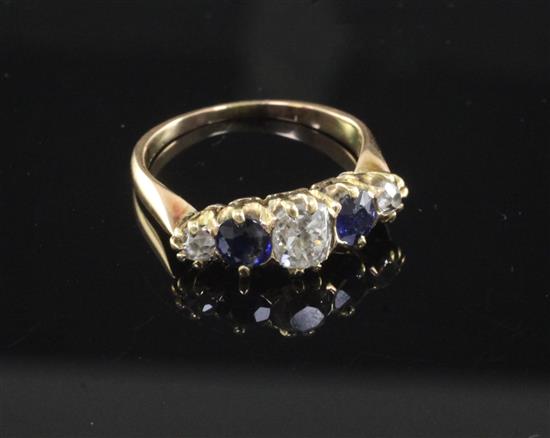 A late 19th/early 20th century gold and graduated five stone diamond and sapphire ring, size L.